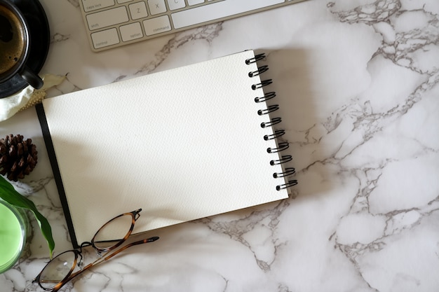 Abra o caderno em branco na mesa de tampo de mármore com material de escritório