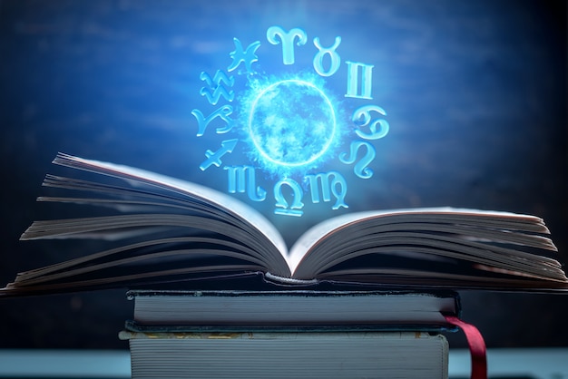 Abra o livro sobre astrologia. O globo mágico brilhante com signos do zodíaco na luz azul