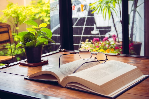 Abra o livro velho com óculos na mesa de madeira no café