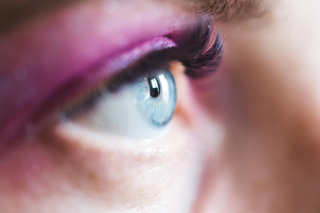 Abra os olhos azuis com sombra rosa e rímel closeup. Foco seletivo.