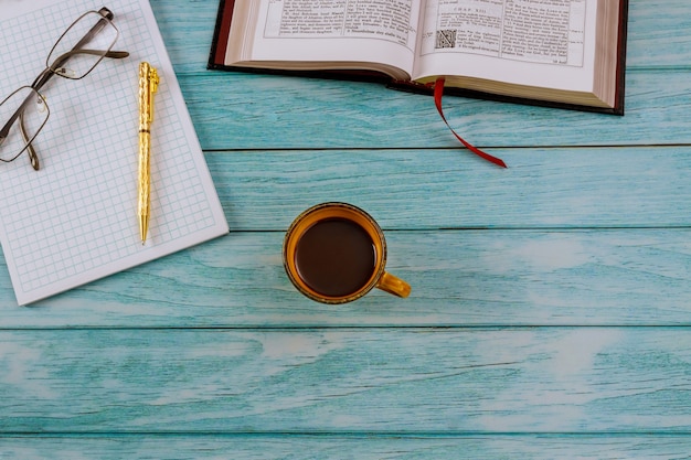 Abra la Santa Biblia acostada sobre una mesa de madera en una lectura con una taza de café