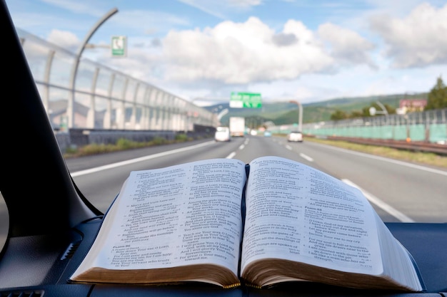 Abra la Santa Biblia dentro del coche con señales de tráfico de fondo en la autopista Tomei, Japón