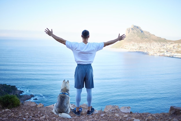 Abraçando a liberdade Foto retrovisor de um jovem irreconhecível e seu husky de estimação apreciando as vistas durante sua caminhada matinal nas montanhas