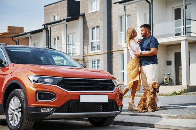 Abraçando-se. Lindo casal passear com o cachorro ao ar livre perto do carro.