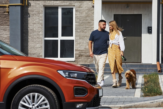 Abraçando-se. Lindo casal passear com o cachorro ao ar livre perto do carro.