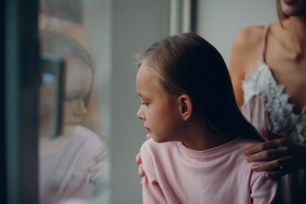 Abraço de mãe com filha. janela olhando menina