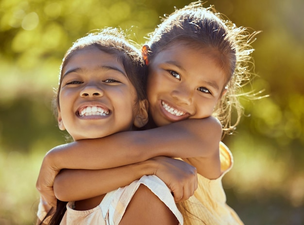 Abraço de menina e irmãs de amor e felizes em retratos juntos crianças ao ar livre e laços familiares na natureza Crianças indianas sorriem relacionamento entre irmãos e cuidam de passar bons momentos no parque