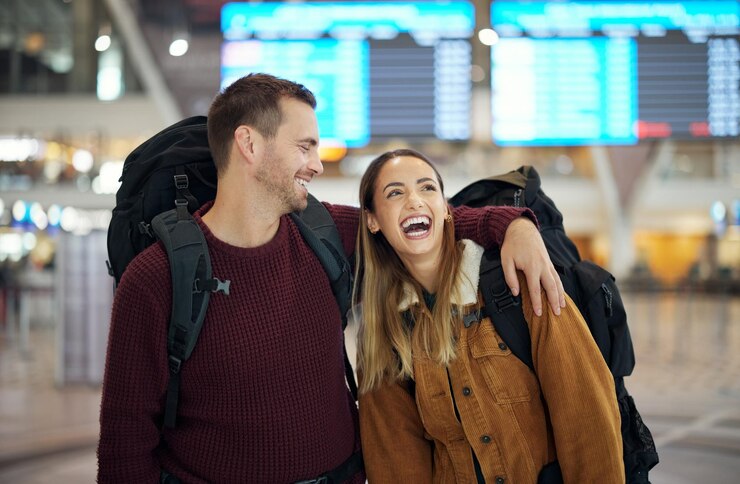 Foto abraço de viagem e casal no aeroporto conversando, conversando ou rindo de uma piada cômica ou engraçada dia dos namorados adora pensar e homem e mulher felizes no saguão da companhia aérea esperando a partida do voo para férias