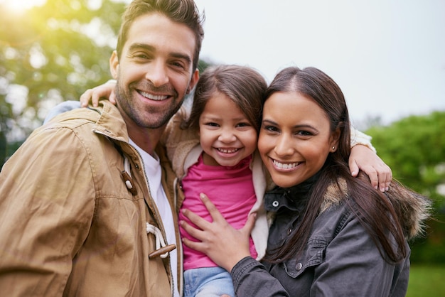 Abraço feliz da família e retrato do parque com uma mãe, pai e filha, juntamente com felicidade e sorriso, rosto ao ar livre e férias de uma mãe, pai e filho, com amor dos pais e cuidados infantis