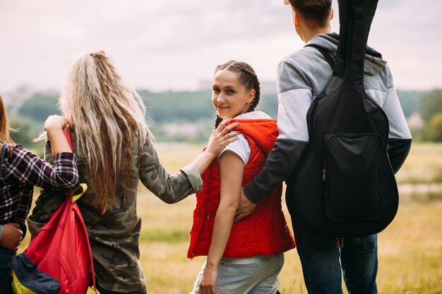 Abraços amigáveis admiram o conceito de turismo de natureza. Unidade do grupo de viajantes. Menina sorridente, olha para trás.