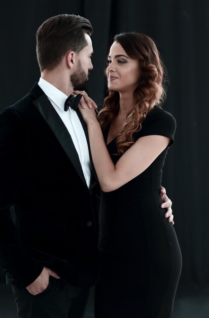 Abraços de homem bonito e mulher de vestido preto sobre fundo escuro Foto de estúdio