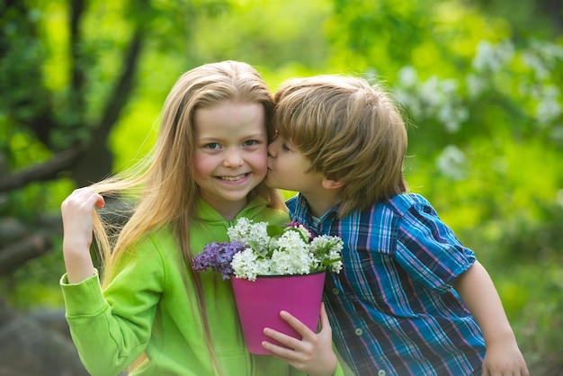 Abrazando y besando a los niños pareja en el jardín pequeños niños encantadores niños al aire libre en el parque de verano clo