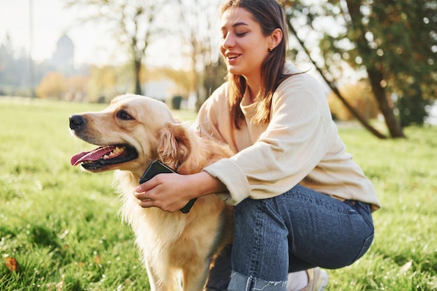 Abrazando a la mascota Mujer joven da un paseo con Golden Retriever en el parque