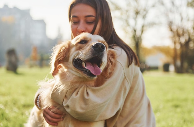 Abrazando a la mascota Mujer joven da un paseo con Golden Retriever en el parque