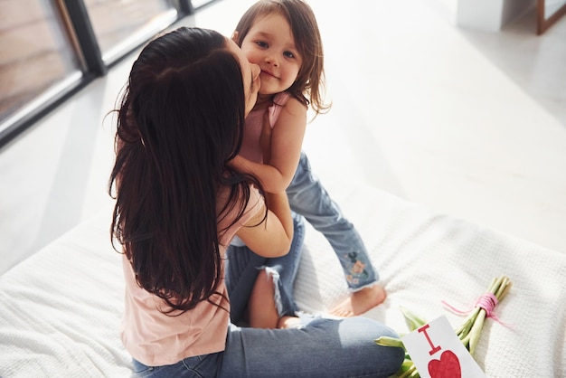 Abrazándose La hija felicita a la madre con las vacaciones y le da un ramo de flores.