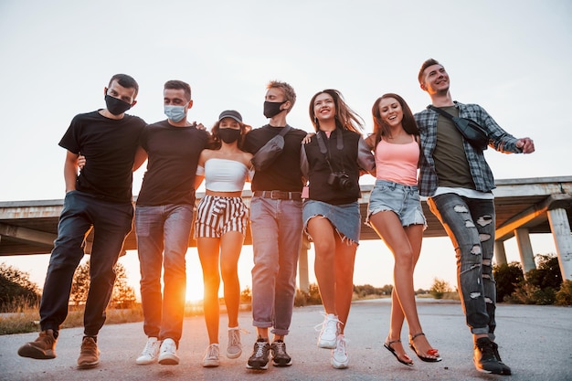 Abrazándose unos a otros Grupo de jóvenes amigos alegres divirtiéndose juntos Fiesta al aire libre