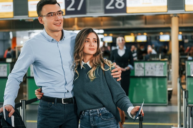 Abrazándose unos a otros Pareja joven está en el aeropuerto juntos