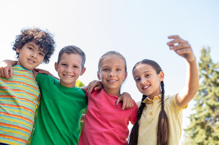 Foto abrazar sonrientes amigos en edad escolar al aire libre