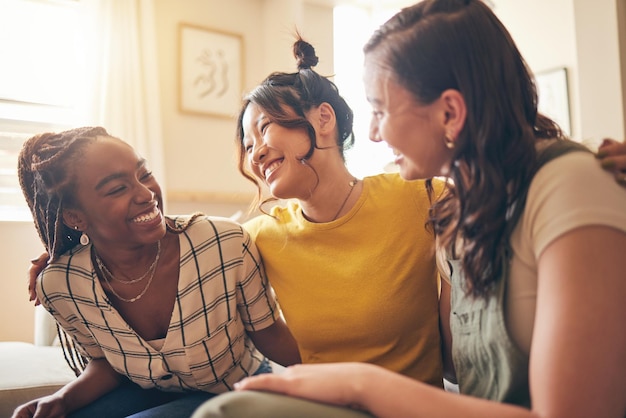 Abrazo feliz y amigas chismeando y vinculándose con cuidado, confianza e historia en su hogar Abrazo de sonrisa y personas con diversidad en una sala de estar con conversación de apoyo y visita social