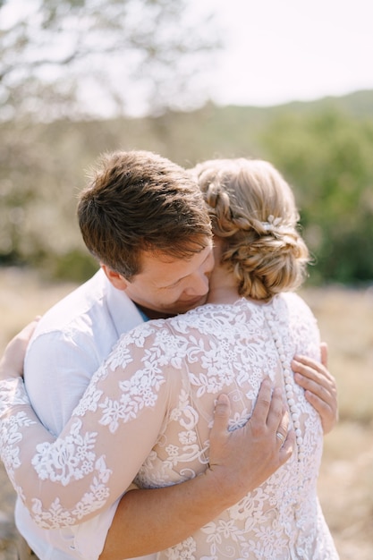 Abrazo de la novia y el novio en el fondo de los árboles closeup