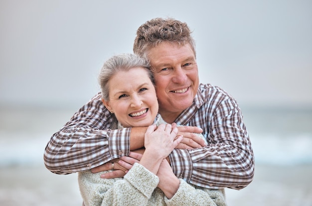 Abrazo en la playa y retrato de una pareja de ancianos relajándose en Australia con una sonrisa de amor y felicidad en la pensión Matrimonio de ancianos y jubilados felices disfrutan juntos de un paseo por el océano