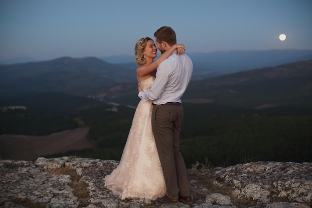 Abrazo de recién casados por la noche en las montañas