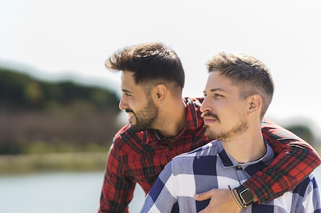 Abrazos gay por detrás de su novio disfrutando de la naturaleza cerca del río