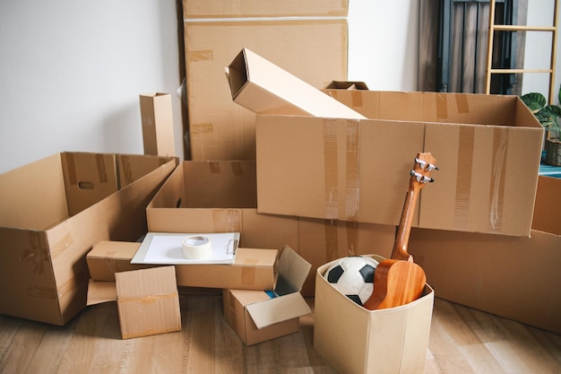 Abre cajas logísticas de cartón con cosas de vivienda Contenedores desordenados colocados en el piso de la nueva casa