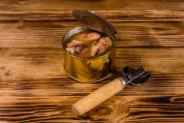 Abrelatas y lata con sardina sobre mesa de madera