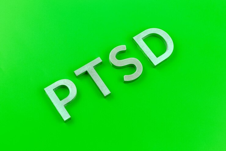 Foto abreviatura ptsd trastorno de estrés postraumático colocado con letras de metal plateado sobre una superficie plana de color verde ácido
