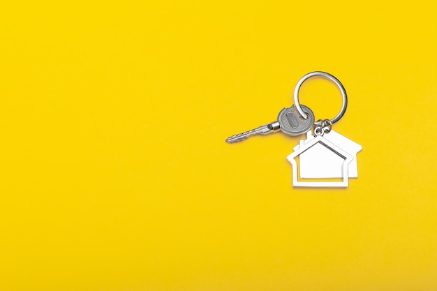 Abrigue chaves com o trinket na cor de fundo, vista superior com espaço da cópia. chave de casa em fundo amarelo. estilo mínimo lay plana com lugar para texto.
