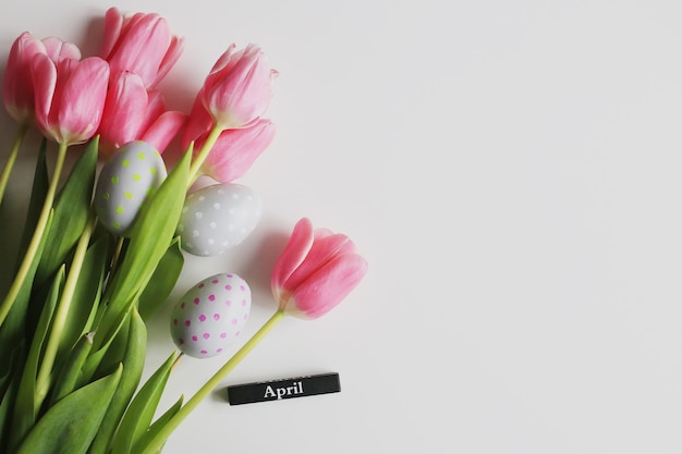 Abril. Fundo de Páscoa com ovos e tulipas cor de rosa. Conceito de férias de primavera.