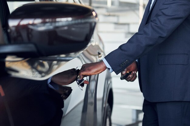 Abrindo a porta Jovem empresário afro-americano de terno preto é o salão automático