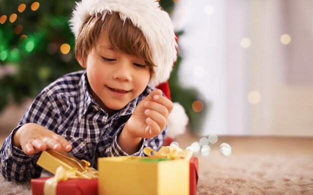 Abrindo seu primeiro presente na manhã de Natal Um menino abrindo um presente no Natal