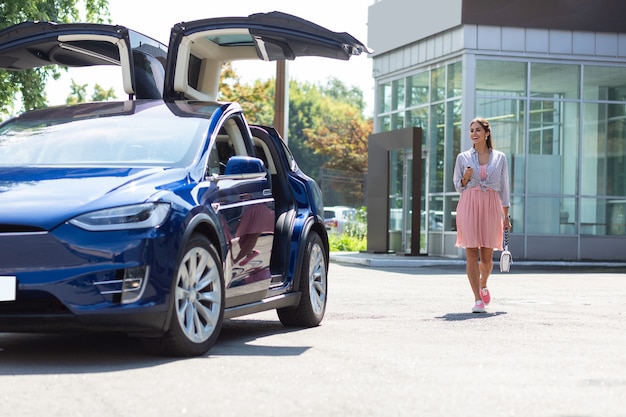 Abrindo um belo carro. elegante jovem empresária abrindo seu belo carro de luxo enquanto caminha até ele