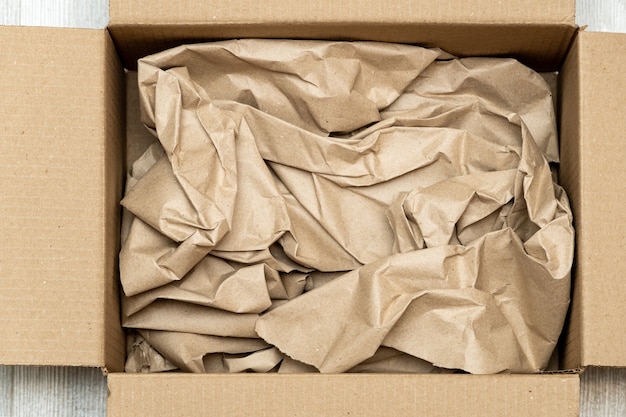 Foto abrir caja de cartón llena de papel de regalo cerrar