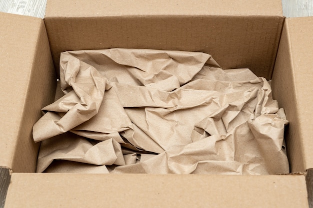Abrir caja de cartón llena de papel de regalo cerrar