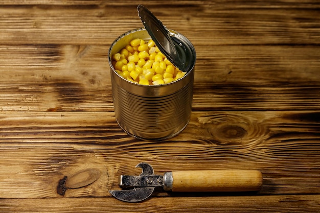 Abrir lata de maíz y abrelatas sobre mesa de madera