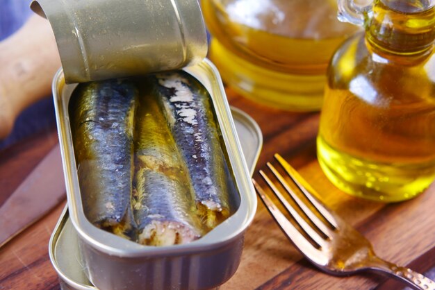 Foto abrir lata de sardinas y aceite de oliva en la mesa