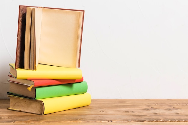 Foto abriu o livro vazio na pilha de livros coloridos na mesa de madeira