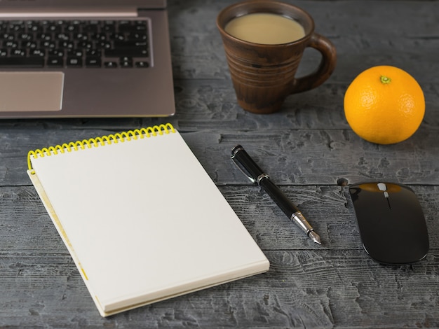 Foto abriu o notebook, laptop, caneta-tinteiro, laranja e mouse em uma mesa de madeira escura