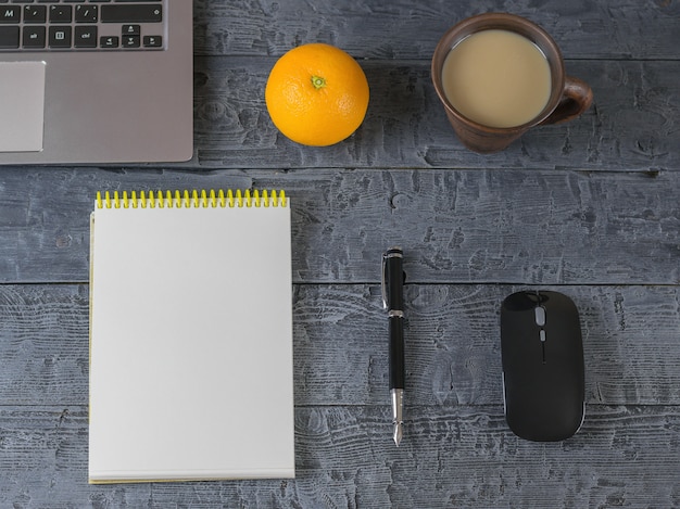 Abriu o notebook, laptop, caneta-tinteiro, mouse e laranja em uma mesa de madeira escura