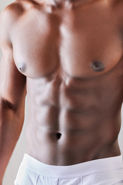 Abs del músculo del estómago y primer plano de la salud y el bienestar del hombre con belleza estética en el estudio Motivación para el cuidado del cuerpo y zoom del abdomen en topless del modelo de fitness africano o culturista en ropa interior