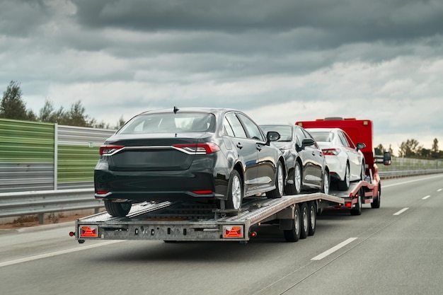 Abschleppwagen mit Autos auf der Autobahn. Abschleppwagen, der ein Auto auf der Autobahn transportiert. Autoservice-Transportkonzept. Rettung am Straßenrand