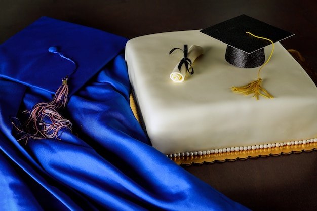 Abschluss-Fondant-Kuchen mit blauem Hut und Kleid auf dunklem Hintergrund.