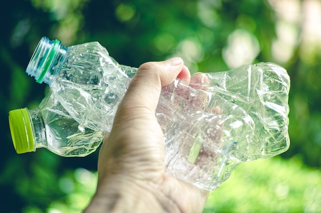 Abschluss oben der Hand, die benutzte zerschmetterte Plastikflasche für die Wiederverwertung hält