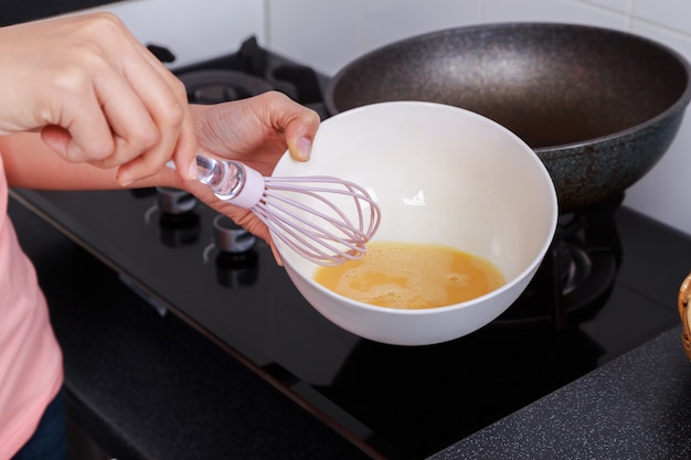 Abschluss oben der Hand, die Eier in einer Schüssel in der Küche kocht und wischt