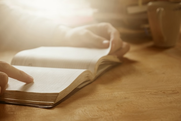 Foto abschluss oben der männlichen hände öffnen ein buch auf hölzernem schreibtisch