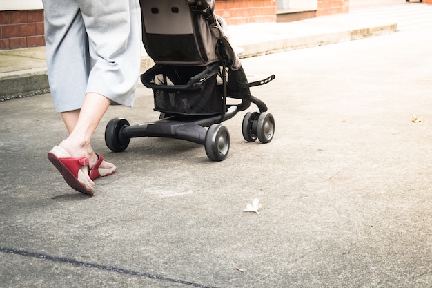 Abschluss oben der Mutter, die mit Kinderwagen geht. Hintergrund für die Reise von Mama und Kind Konzept