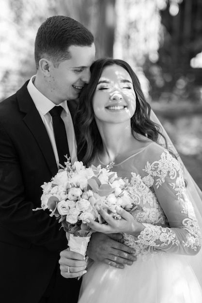 Absolut atemberaubendes junges Hochzeitspaar, das im Wald spaziert und posiert.